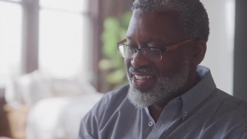 A man smiles while looking down