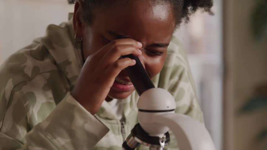 Smiling girl using a microscope