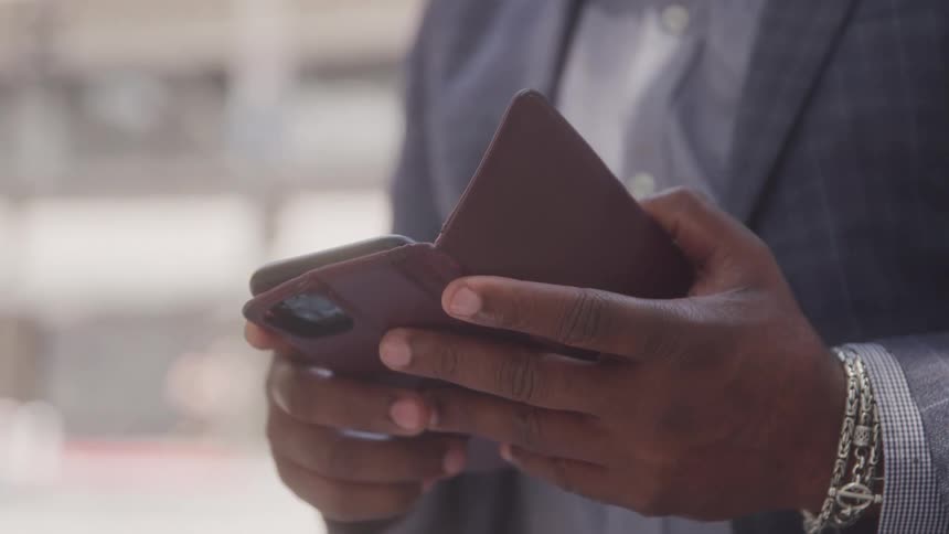 Close up of a black businessman using a mobile phone while standing outdoors during daytime