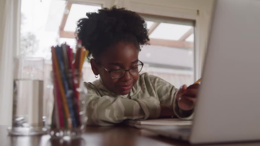 Girl sitting at a table writing with a pencil