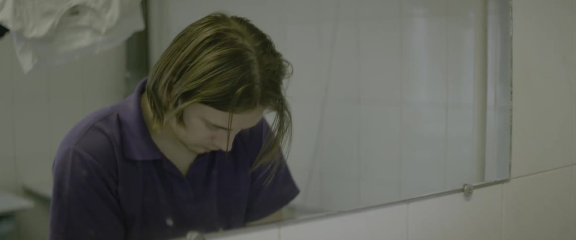 A man is working on something in front of a mirror