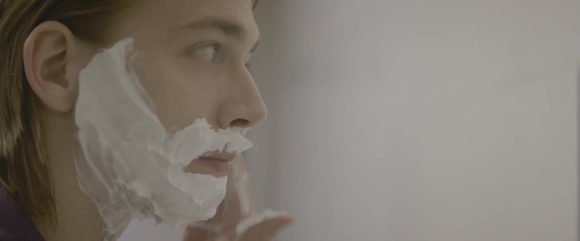 A man applies shaving cream to his face