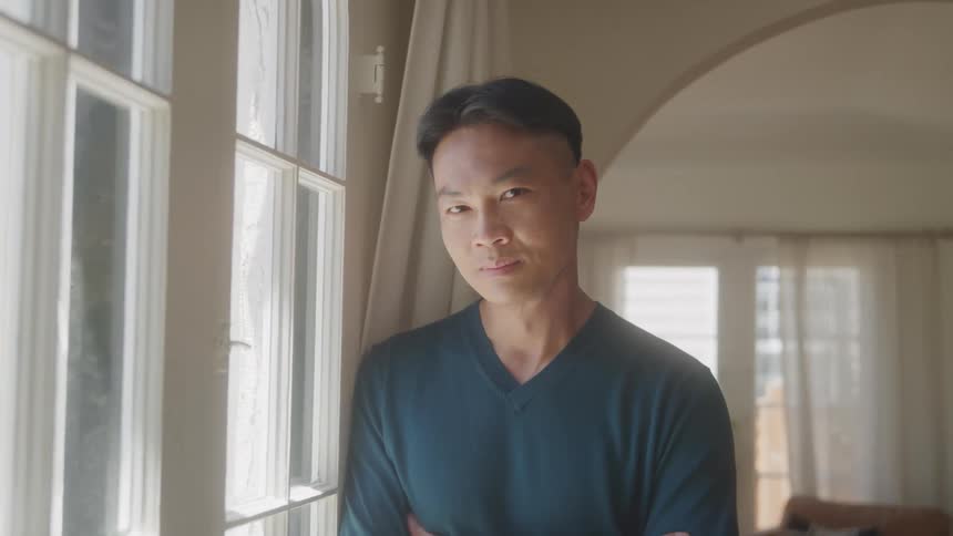 Man looking out the window turns his head to face the camera