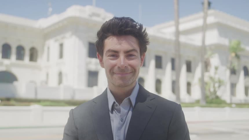 Man in suit with happy expression with classic building in background