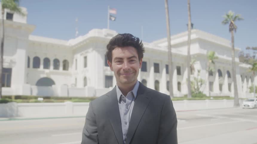 The man is standing outside smiling