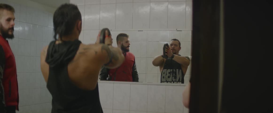 Two men are lifting weights in front of a mirror
