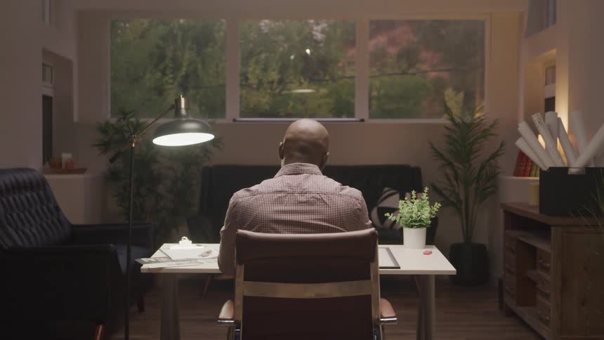 A black man works while sitting at a desk in an office during daytime