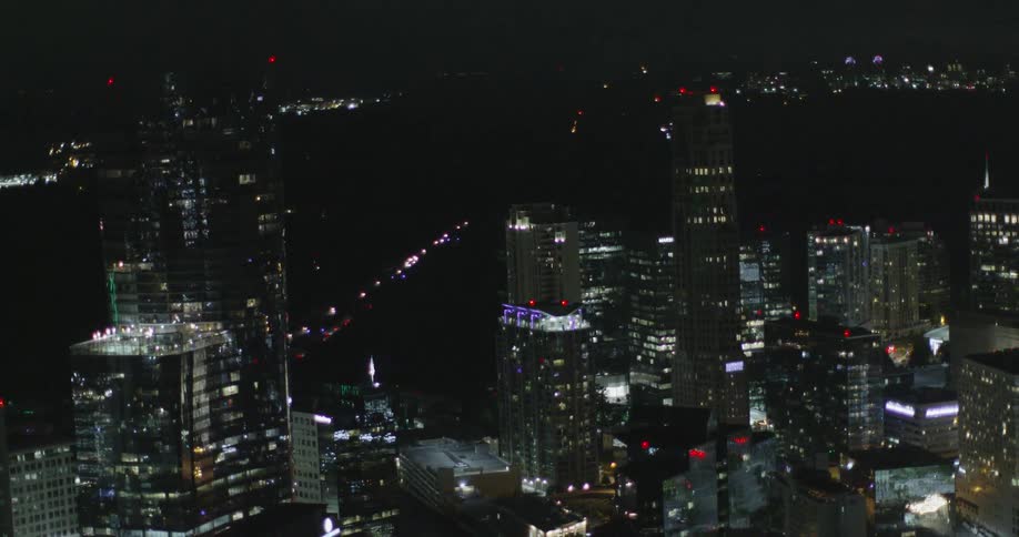 Tall buildings reflect the bright lights all around at night