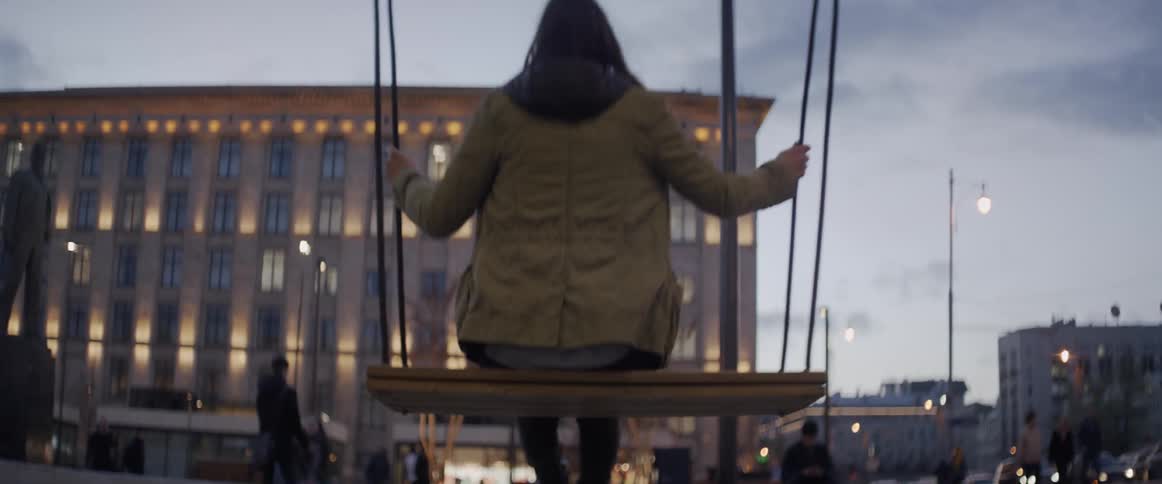 A woman swings on a swing in a city plaza
