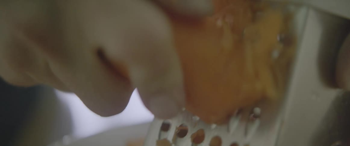 A carrot is being grated on a grater