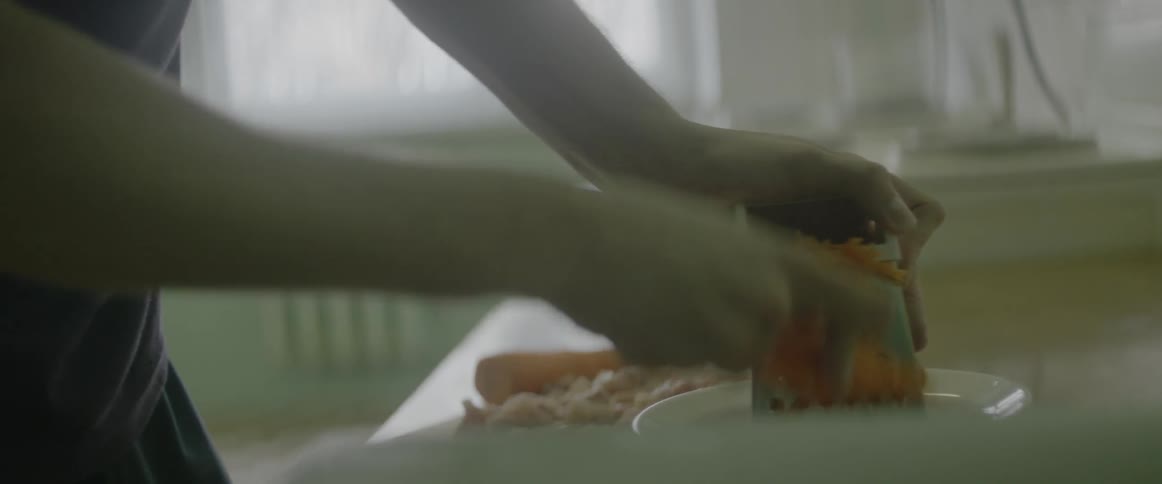 A person is cutting carrots with a grater