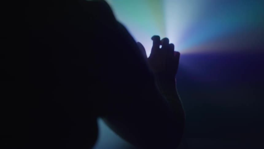 Silhouette of a hand towards an abstract light