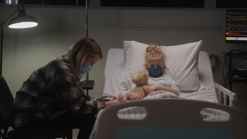 Mother comforts her sick daughter in a hospital bed