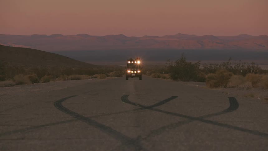 Vehicle drives on a remote road at sunset