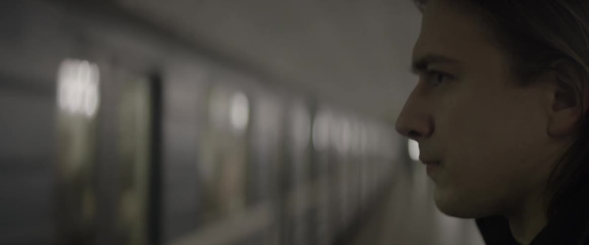 Man standing in a subway station watching as the train approaches