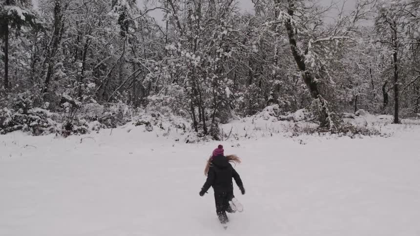 Little girl running in a snowcovered environment with a forest in the background