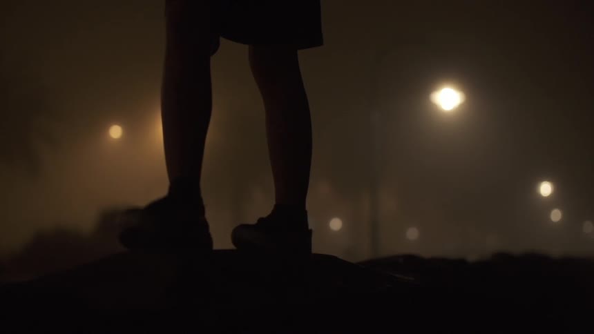 A person walking outside at night with lamp posts in the background