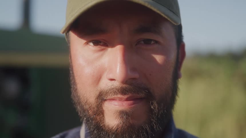 Close up portrait of a young male standing on a field outdoors during daytime