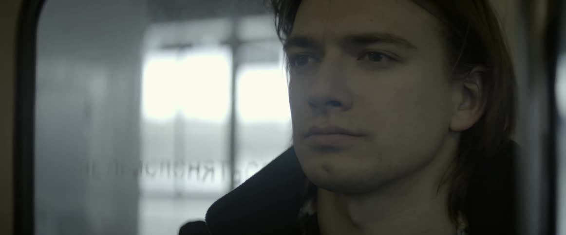 A man is sitting in a train looking forward