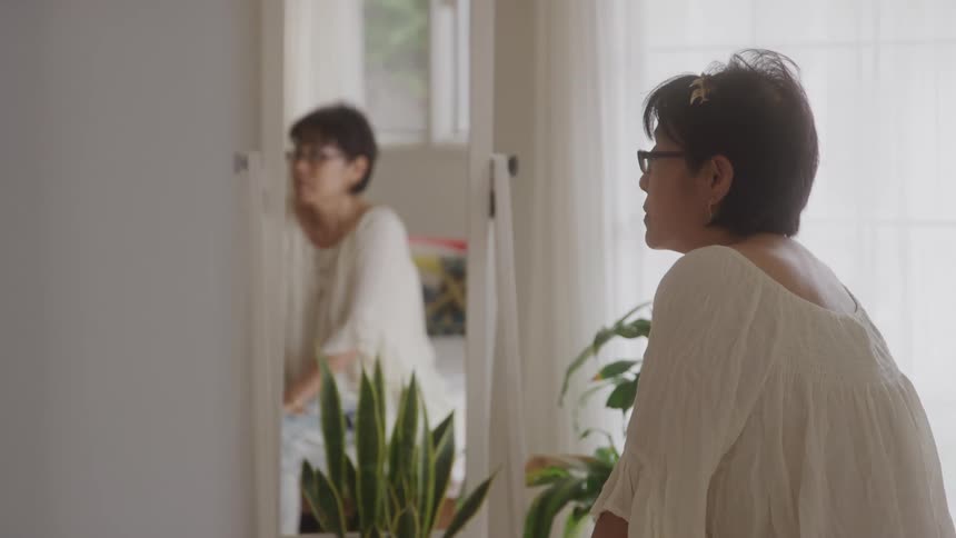 Woman in a room of the house with a mirror next to her