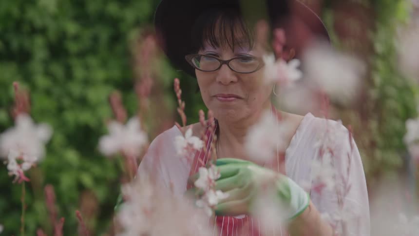 Woman in a hat gardening in a backyard