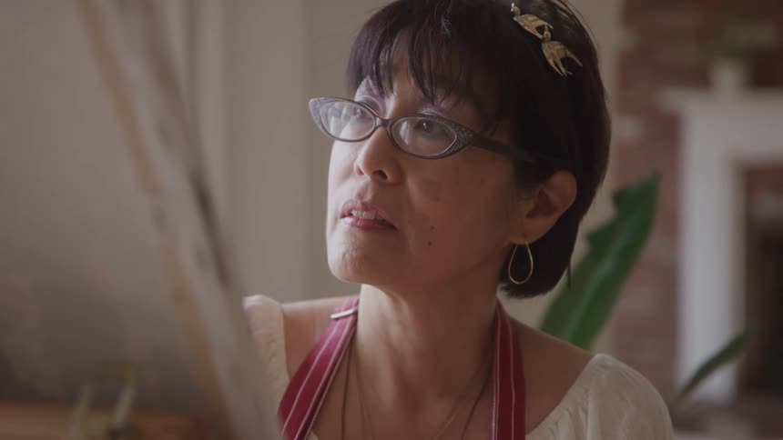 Woman with glasses focused on painting a canvas