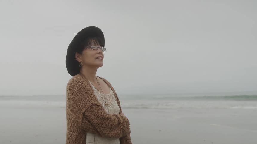 Woman in a hat on a beach on a cloudy day