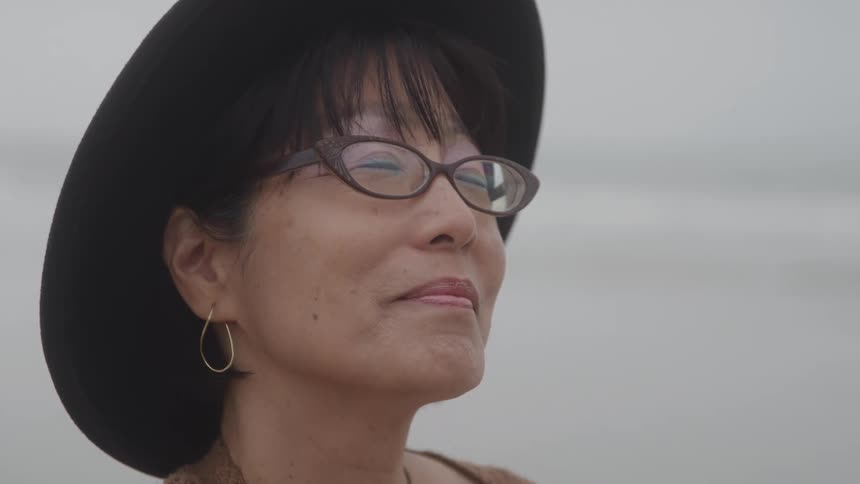 Woman in hat and glasses with the sea in the background