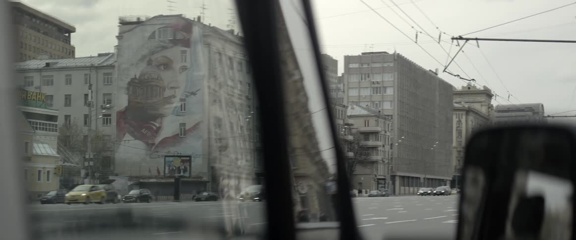 Cars pass by housing buildings on a cloudy day