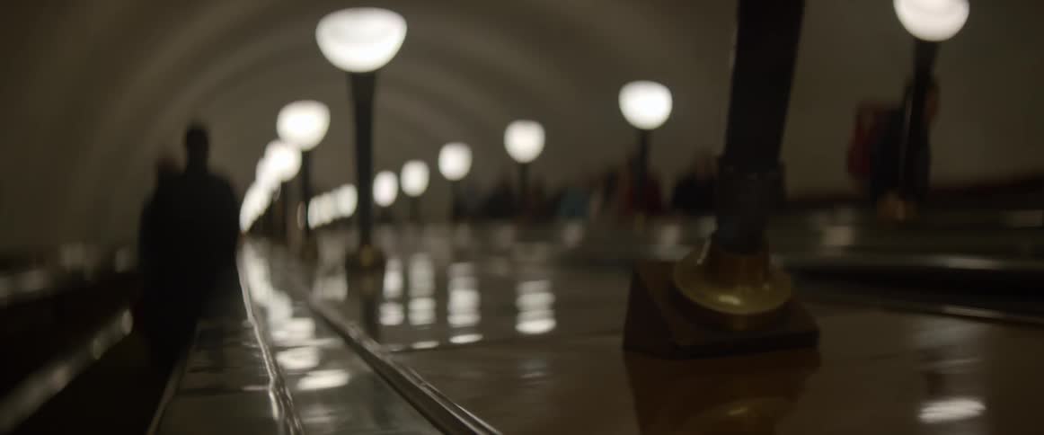People ride an escalator lined with lamps