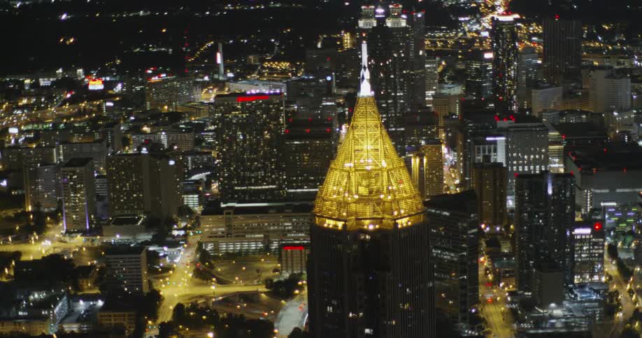 An aerial view of a city and a higher peak building that is lit up yellow