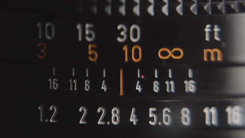 The aperture and depth of field scale on a vintage camera lens scrolling left and right