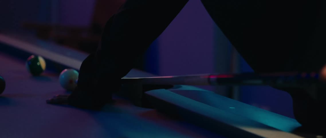 Pool player takes a shot while leaning over the pool table