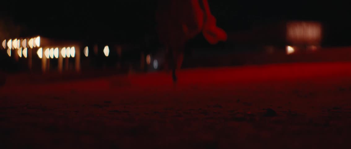 Woman in high heels running outdoors at night with red lights