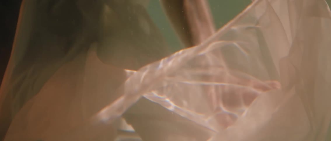 A serene underwater ballet where a persons body and flowing sheer fabric move together in a slow dreamlike dance