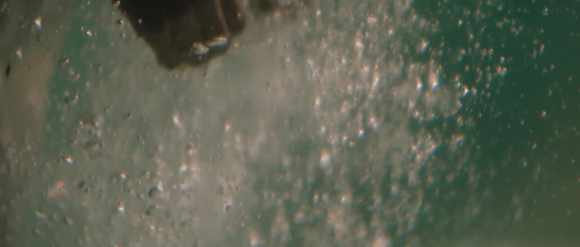 Persons hand moving underwater with bubbles