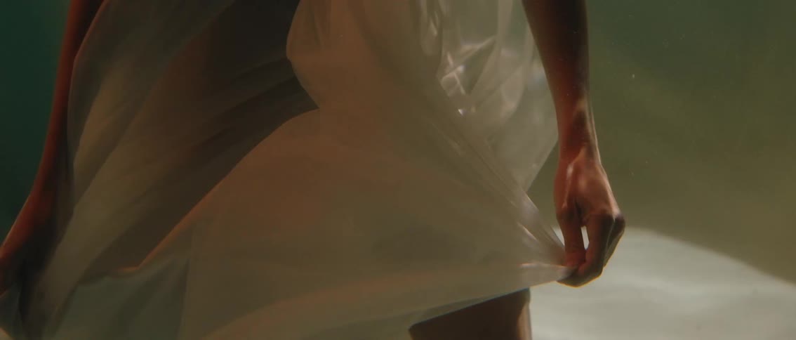 Body of a woman submerged in water wearing a white dress