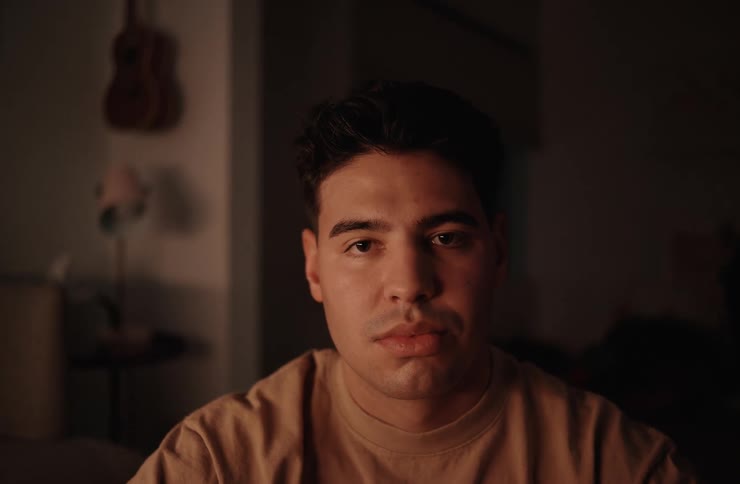 Man stares while sitting in a dimly lit room