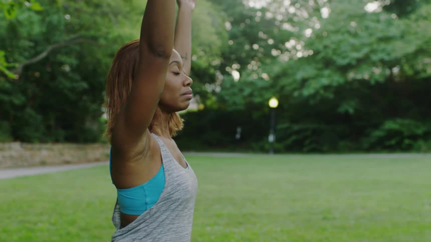 A woman is doing yoga on a grass field