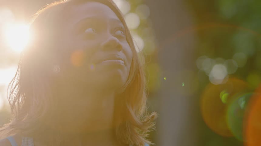 A woman smiles and looks up at the sunny sky