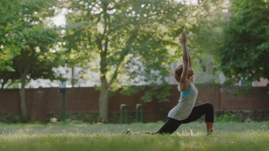 A woman does yoga outside on a sunny day