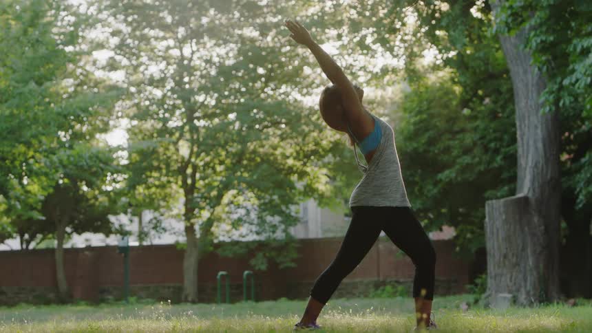 A woman is stretching doing yoga on a sunny day