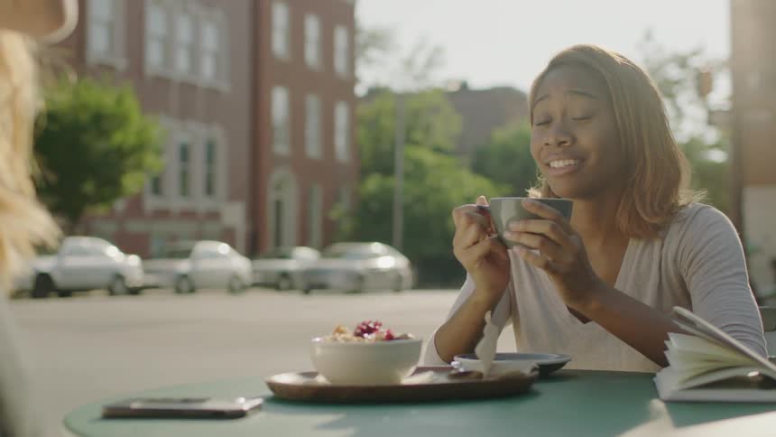 A couple of women sitting at a table outside a diner and talking and smiling