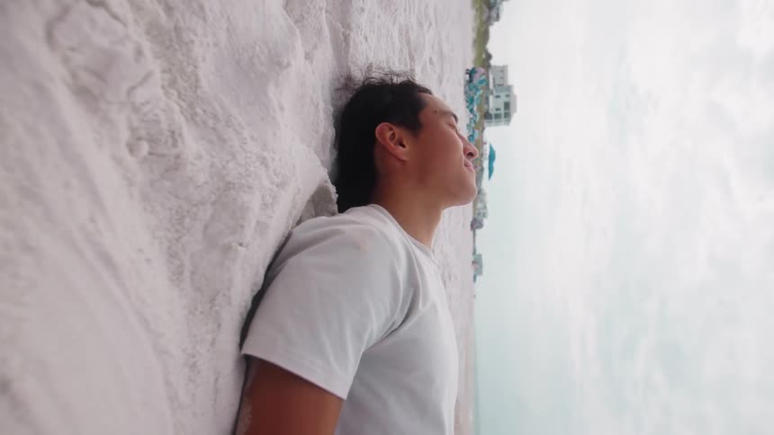 A young man lies on the beach sand outdoors during daytime