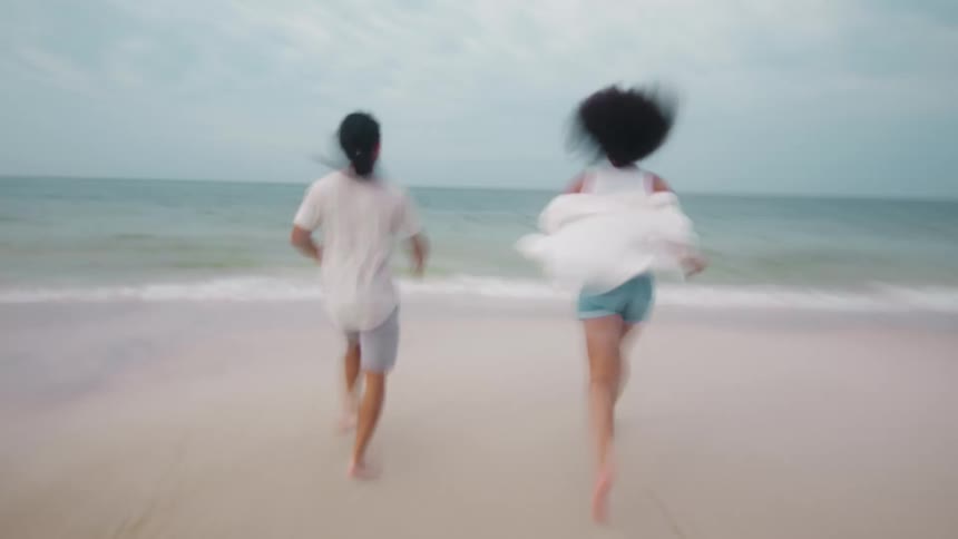 Two people race towards the surf