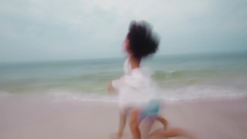 Two people holding hands running on the beach