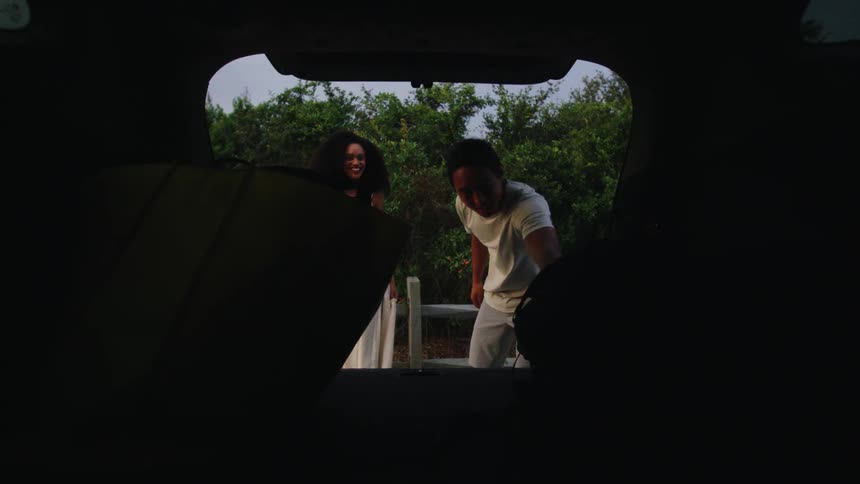 Couple taking a backpack from a trunk