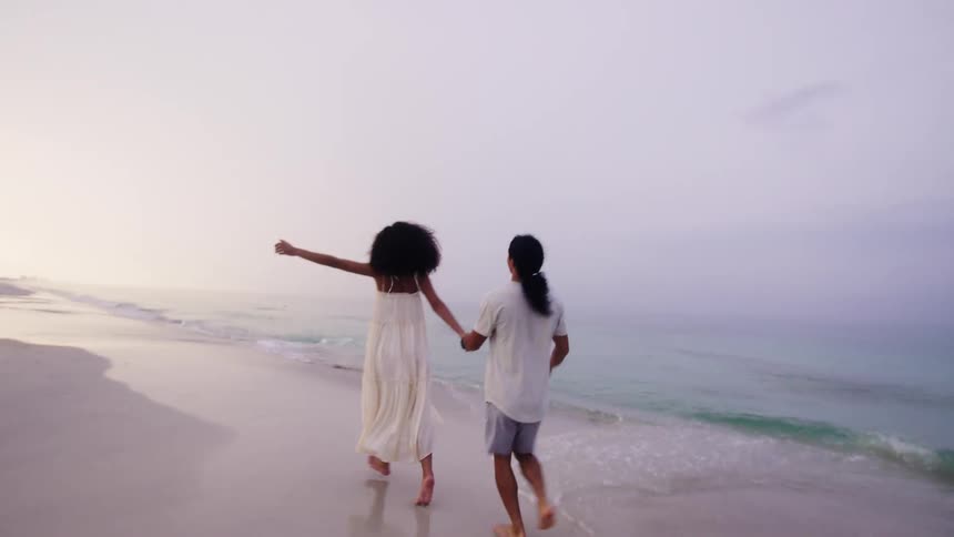 Couple in white running on the beach romantically