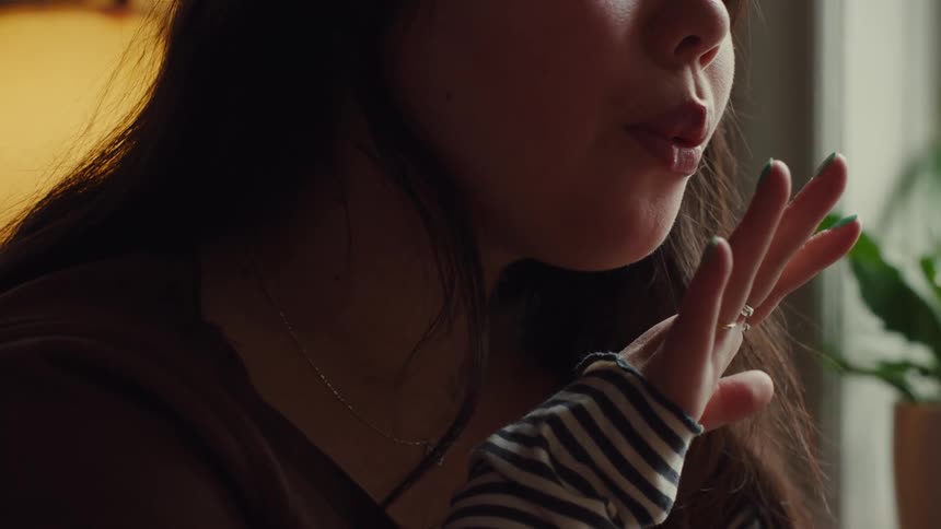 Female blowing on her freshly painted nail polish to dry