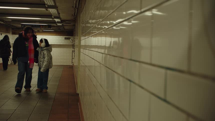 A parent and child walk together through an empty subway station